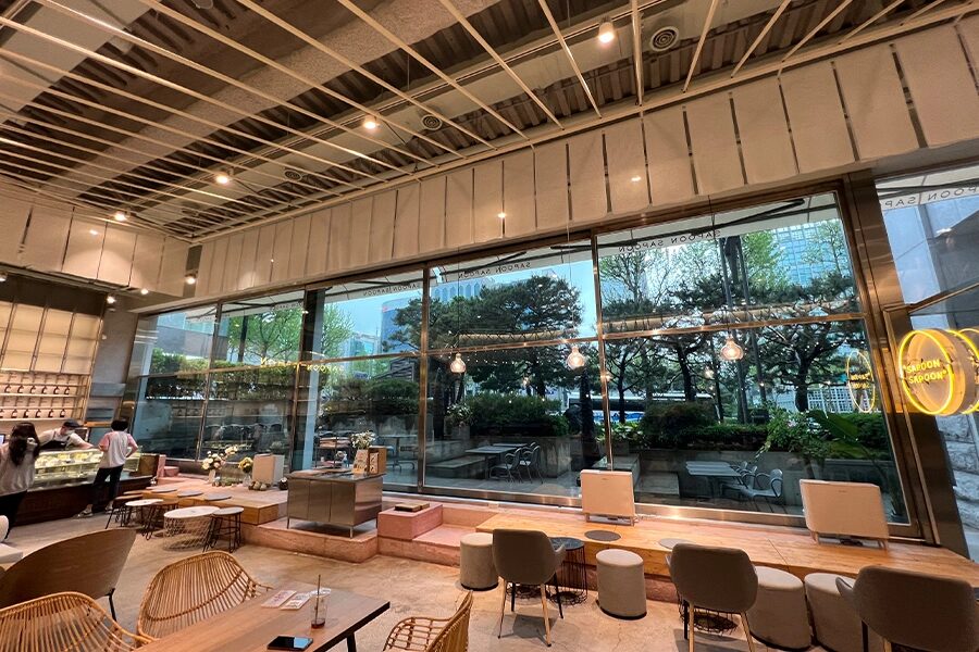 저녁 조명이 켜진 카페 내부, 통유리 너머 정원 전경