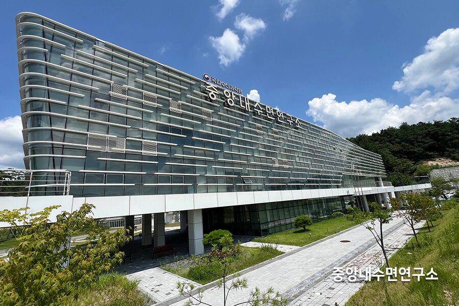 강변에 자리한 곡선형 통유리 연구소 건물 외관