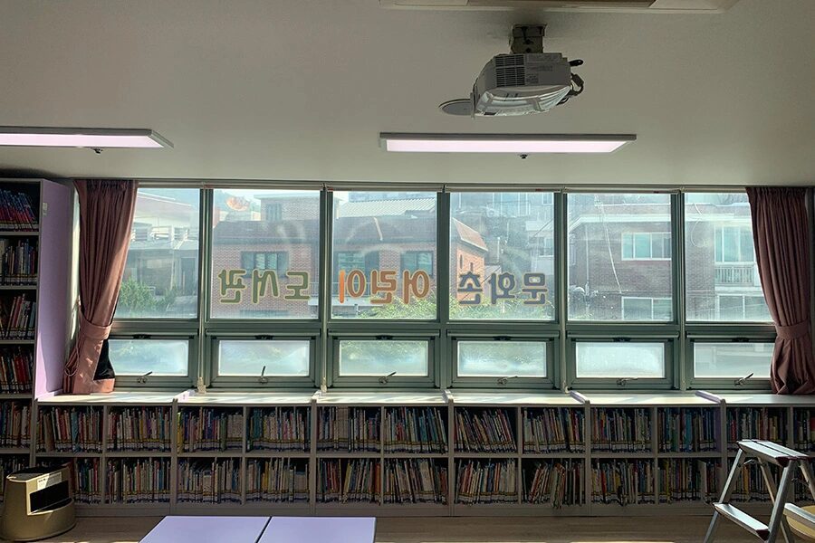 창을 따라 책장이 길게 이어진 작은도서관 내부